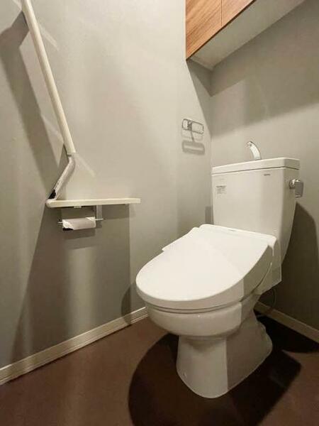 画像8:【トイレ】落ち着く色調のトイレ。上部吊戸棚、手摺、小物置きに使えるペーパーフォルダー天板があり、機能