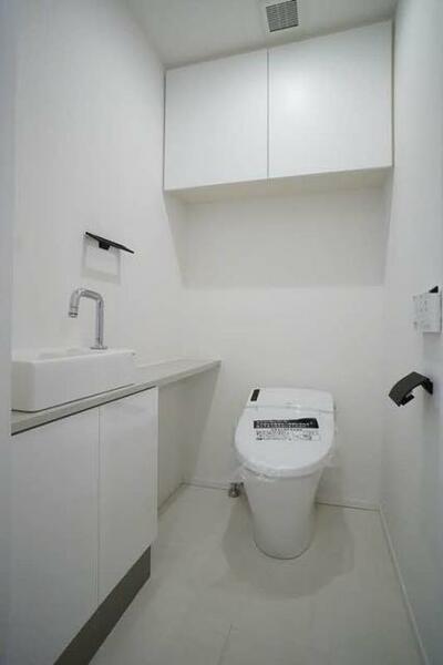 画像15:タンクレスの多機能便座付きトイレです。カウンターの手洗い器があります。便利な吊り戸棚もあり備品をスッ