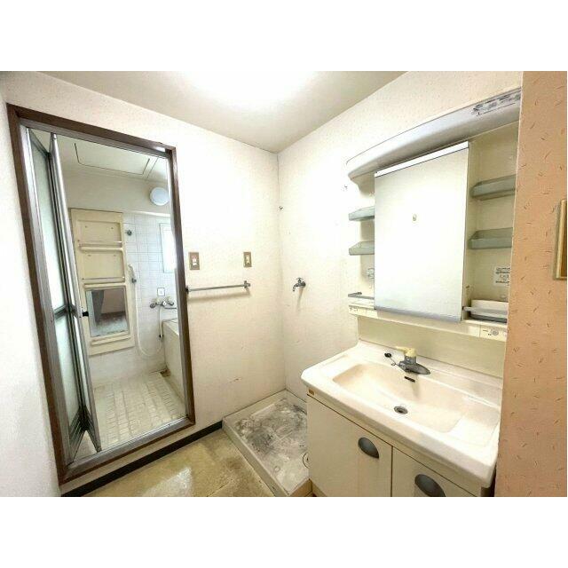 洗面台と洗濯機置き場がコンパクトにまとまった実用的な脱衣スペース。鏡周りには収納棚も備え付けられてお