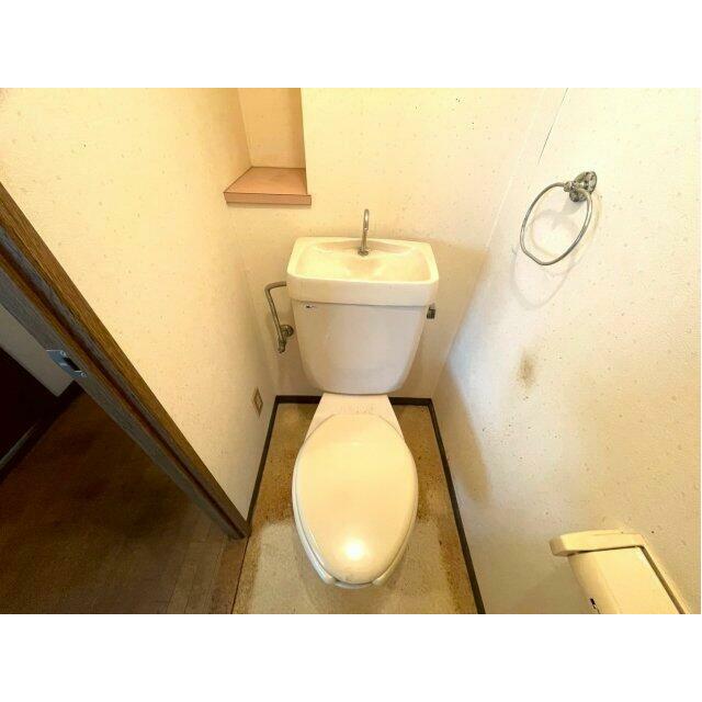 シンプルで清潔感のあるトイレスペース。背面には小物を置ける棚があり、芳香剤や装飾なども楽しめます。