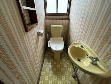 窓から自然光が差し込むトイレ空間です。レトロなデザインで落ち着いた雰囲気。棚もあり、小物の収納にも便