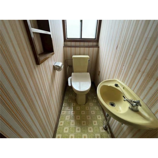 窓から自然光が差し込むトイレ空間です。レトロなデザインで落ち着いた雰囲気。棚もあり、小物の収納にも便