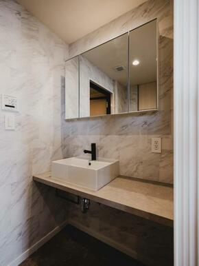 大理石調の洗面スペースは高級感があります。ミラーボックスの中にサニタリーグッズを収納することも。