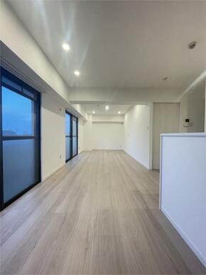 明るい木目調の床とダウンライトが印象的なリビング。窓から差し込む光が空間をさらに開放的に演出し、家族