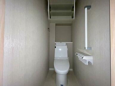 シンプルで清潔感のあるトイレ空間。上部には便利な吊戸棚があり、トイレットペーパーや掃除用品などのスト
