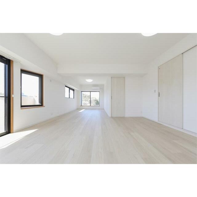 明るい陽光が差し込む広々としたリビング。白を基調とした内装と明るいフローリングが開放感を演出します。