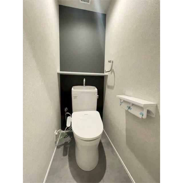 壁の一部にアクセントクロスを採用した、落ち着いた雰囲気のトイレ。手洗いボウルと収納棚を設置し、機能性