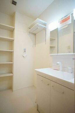 洗面所　洗髪洗面化粧台を設置、洗濯機置き場上部には棚が２段ございます。