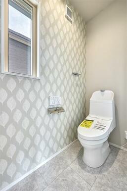 ２階トイレ。清潔感のある白いトイレに、やさしい色味のアクセントクロスが空間全体に温かみを与えています