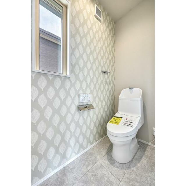 ２階トイレ。清潔感のある白いトイレに、やさしい色味のアクセントクロスが空間全体に温かみを与えています