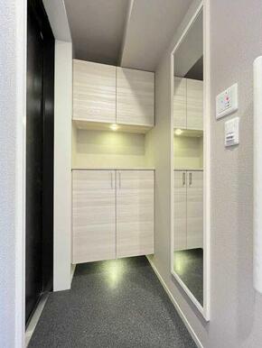 【玄関】ホワイトの木目調がアクセントなセパレートタイプのシューズボックスがある玄関。姿見があり出掛…