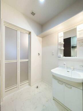 洗面台の横には洗濯機置場。脱衣所はちゃんと建具で仕切られております。また、上部には棚がございます！