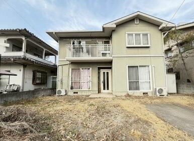 落ち着いた色合いが印象的な二階建て住宅。前面にゆとりのある敷地が広がり、陽当たりも確保されています。