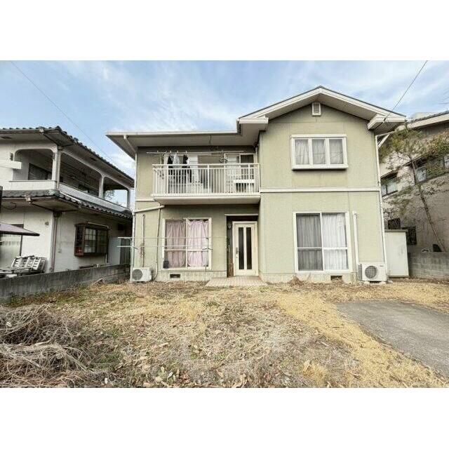 落ち着いた色合いが印象的な二階建て住宅。前面にゆとりのある敷地が広がり、陽当たりも確保されています。