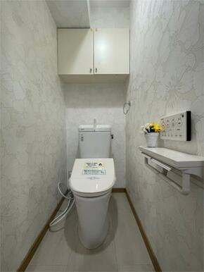 清潔感あふれるトイレは、爽やかな花柄の壁紙が印象的。吊戸棚や飾り棚も設置され、収納力と使いやすさを両