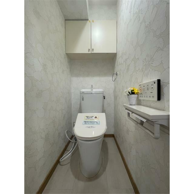 清潔感あふれるトイレは、爽やかな花柄の壁紙が印象的。吊戸棚や飾り棚も設置され、収納力と使いやすさを両