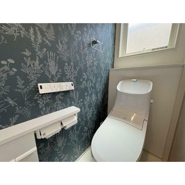落ち着いたボタニカル柄のアクセントクロスが印象的なトイレ空間。温水洗浄便座を備え、毎日快適にご利用い