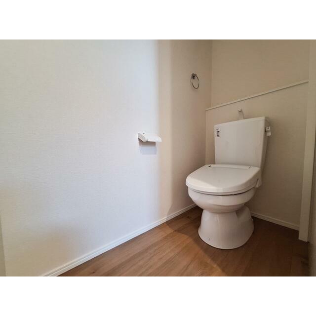 明るくシンプルなトイレ空間です。壁や床のカラーが清潔感を感じさせます。ペーパーホルダーなども設置され使いやすさが考慮されています。全体的にゆとりのあるつくりとなっています。