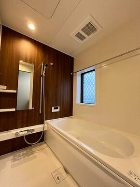 「浴室」ダークブラウンのアクセントパネルを使用し、温かい空間です。