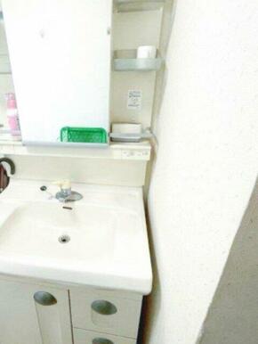 洗面台と洗濯機置き場がコンパクトにまとまった実用的な脱衣スペース。鏡周りには収納棚も備え付けられてお
