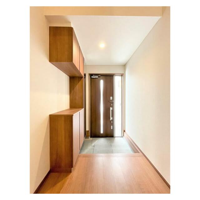 玄関は、温かみのある木目調収納棚とブラウンのドアがアクセントになっています。