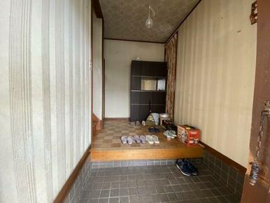 木製の重厚感ある玄関ドアと採光窓が特徴のエントランス。シンプルながらも広めの玄関スペースで、収納やイ