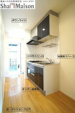 ダークブラウンのシステムキッチン。廊下としてもキッチンとしてもスペースはゆったりしております。