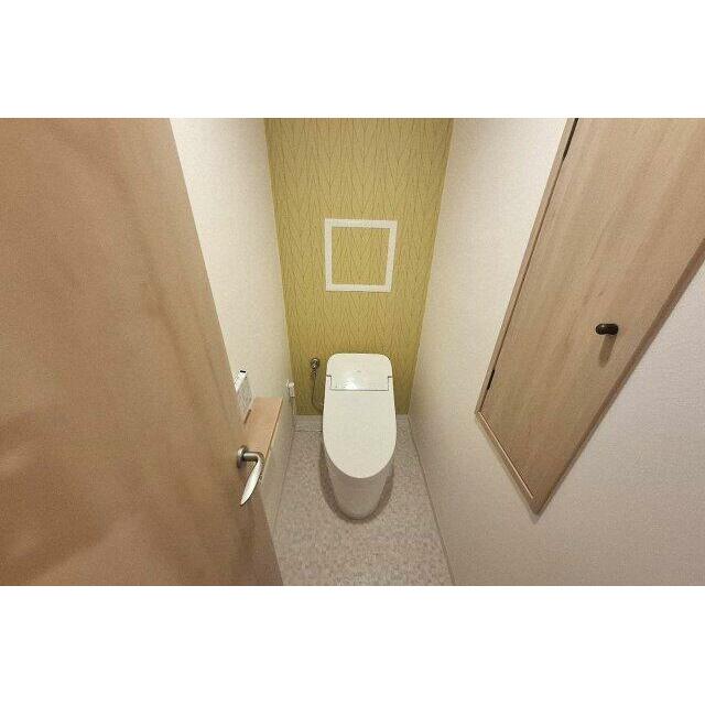 トイレ内の壁や床、入口建具は新調済み。明るいイエローのアクセントクロスが印象的です。