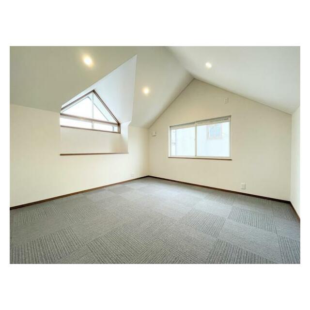 小屋根裏部屋のような傾斜天井が特徴で、ダウンライトが部屋全体を明るく照らす空間です。