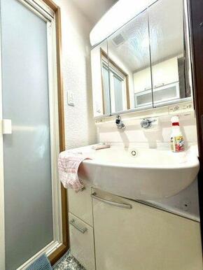 三面鏡付きの洗面化粧台。明るい照明と広々としたボウルで、朝の身支度も快適。清潔感あふれるデザインです