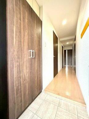 木目の建具と明るいフローリングが調和した清潔感ある玄関。収納も備え、住まいの第一印象を美しく整えます