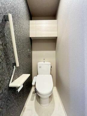 【トイレ】シャワートイレ仕様です。一面タイル調のアクセントクロスです。トイレ上部には扉付きの収納棚…