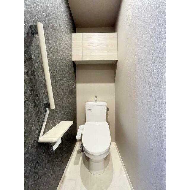 【トイレ】シャワートイレ仕様です。一面タイル調のアクセントクロスです。トイレ上部には扉付きの収納棚…