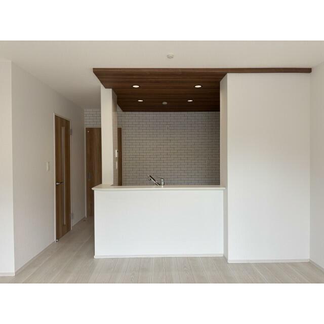 【キッチン（7号棟）】木目調の下がり天井とレンガ調のアクセントクロスが空間にアクセントを添える、おし