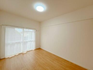 「北西側洋室　約5.7帖」バルコニーへ出られる窓にレースカーテンがございます。