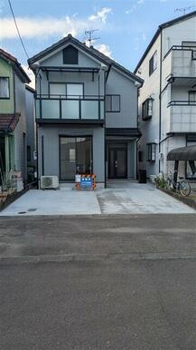 モダンで落ち着いたグレーの外壁と清潔感のあるタイル敷きの駐車スペースが印象的な住宅です。