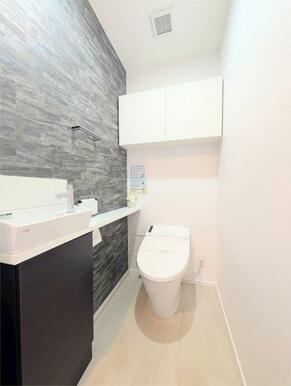 スタイリッシュなアクセントクロスが印象的なトイレ空間。手洗いカウンターや吊戸棚も備え、機能性とデザイ