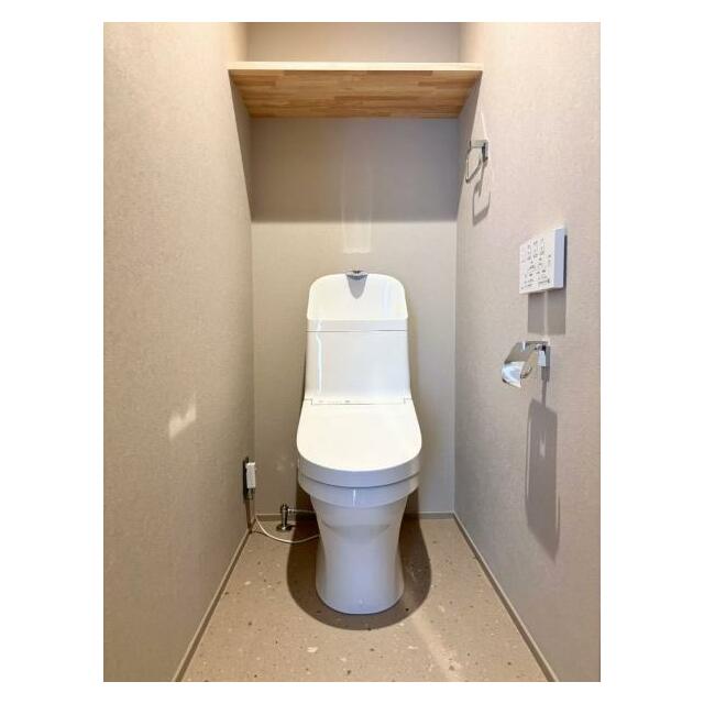 シンプルで洗練されたトイレスペース。収納棚が空間のアクセントとなり、実用性と意匠性を両立しています。