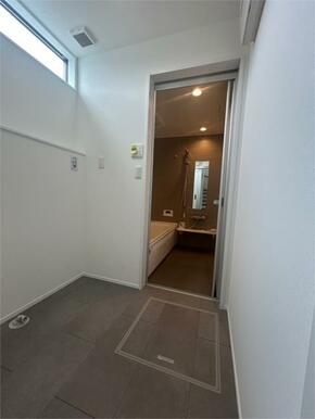 高窓から陽が差し込む明るい脱衣室。洗濯機置き場からお風呂へ直行できる効率的な動線で、家事もラクです。