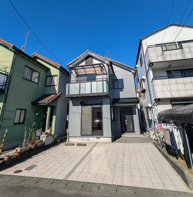 モダンで落ち着いたグレーの外壁と清潔感のあるタイル敷きの駐車スペースが印象的な住宅です。