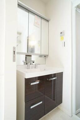 洗面台は正面鏡が３面鏡になるタイプです。鏡の裏には小物収納が配置されています。キャビネットはキッチン