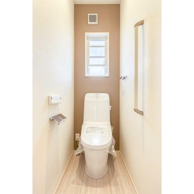 １階トイレです。温水洗浄便座、ペーパーホルダー、タオル掛け付きです。換気・採光の出来る窓もあります。