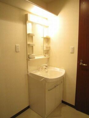 ノズルが伸びて洗髪も可能な洗面化粧台。隣は洗濯機置場です。スペース上部には収納棚も付いています。