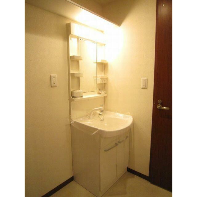 ノズルが伸びて洗髪も可能な洗面化粧台。隣は洗濯機置場です。スペース上部には収納棚も付いています。